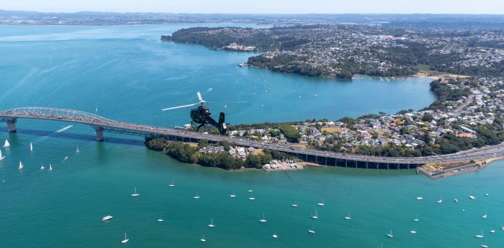 aerial-view-of-harbour-bridge-and-north-shore-with-black-helicopter-with-boats-in-the-ocean-2