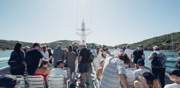 groups-of-people-on-the-top-deck-of-a-ferry-getting-up-as-the-boat-pulls-into-matiatia-wharf-on-waiheke-island-in-auckland-2